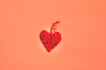 Valentines Day concept. Creative paper background with wicker heart. Living Coral trendy color. Top view, copy space, closeup.