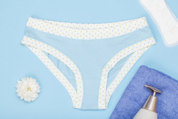 Beautiful women's panties with a sanitary napkin and towel on blue background.