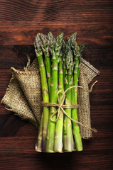 Raw asparagus on a brown wooden surface.