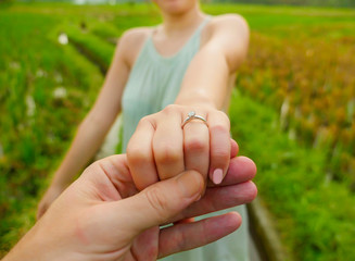 close up couple hands man holding happy fiance hand with diamond engagement ring on her finger after wedding proposal at tropical beautiful and romantic spot