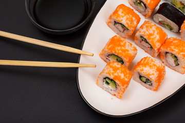 Uramaki California. Sushi rolls, wooden sticks and bowl with soy sauce.