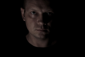 Portrait of a serious man face in darkness.