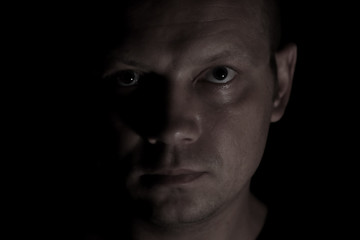 Portrait of a serious man face in darkness.
