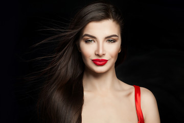 Sexy woman brunette with dark straight hair and red lips makeup. Happy girl on black background
