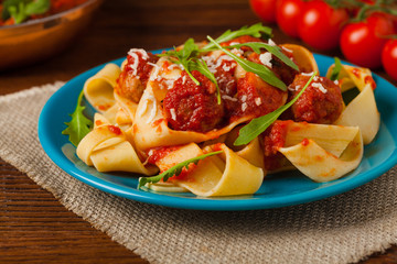 Italian pasta pappardelle with meatballs in tomato sauce.