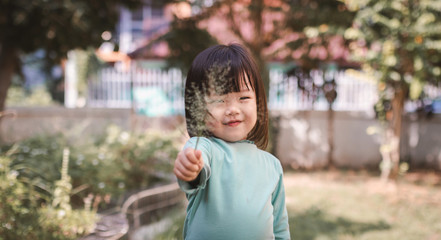 Fototapeta premium portrait of happy asian little girl hand holding grass flower.