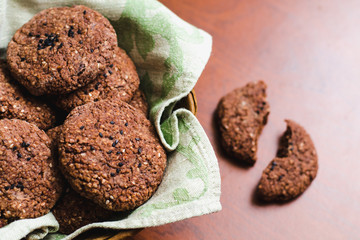 Homemade chocolate oatmeal cookies with white and black sesame seeds on a brown wooden table