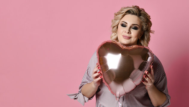 Woman hold heart balloon smiling on pink background. Love valentines day