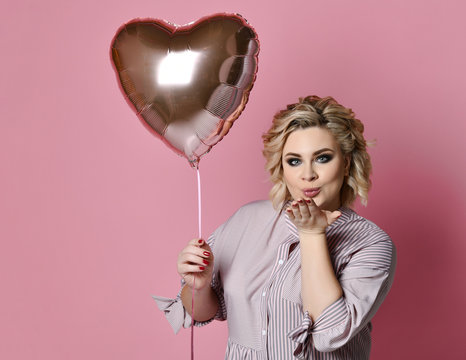 Woman with heart balloon on pink background blowing kiss. Love valentines day 