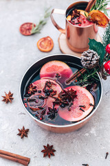 Mulled wine hot drink with citrus, apple, pomegranate and spices in aluminium casserole with vintage Сhristmas decorations