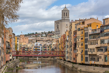 Fototapeta premium Colorful yellow, red and orange houses with the Catalan flags reflected in water river Onyar, in Girona, Catalonia, Spain.
