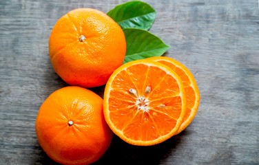 Orange fruit with its leaves lay on a wooden floor.