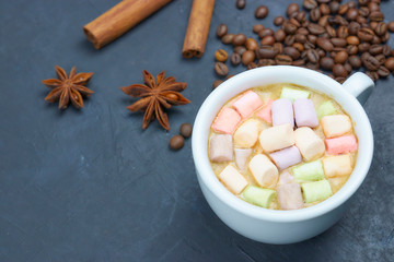 coffee drink with marshmallows and spices. on a dark background. view from above. copy space. morning refreshing drink.