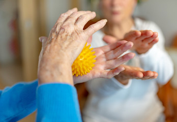 Rentnerin macht Lockerungsübungen mit einem Igelball