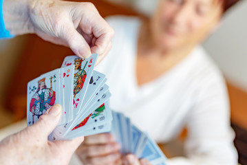 Rentnerin spielt mit Pflegekraft Karten