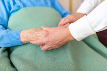 Rentnerin hält die Hände gefaltet und mit einer Decke zugedeckt