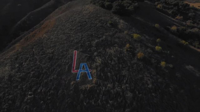 Reverse reveal shot of the LA sign with clouds iand sky n the background.