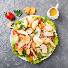 Caesar salad with chicken breast on gray background