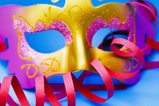 Carnival mask, streamers and confetti on bright blue background