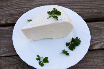 Bryndza in a plate on wooden table. Top view