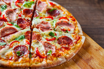 Pizza with Mozzarella cheese, ham, tomato sauce, salami, pepper, Spices and Fresh arugula. Italian pizza on wooden table background