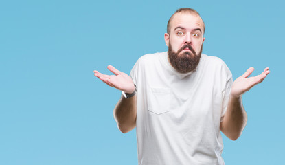 Fototapeta premium Young caucasian hipster man wearing casual t-shirt over isolated background clueless and confused expression with arms and hands raised. Doubt concept.