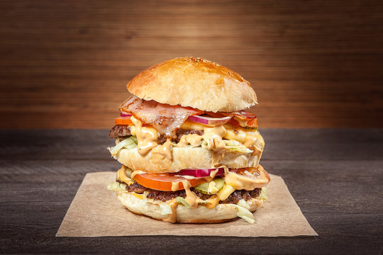 Hamburger with fried meat and vegetables on wrapping paper