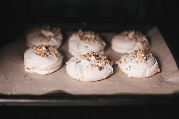 meringue with walnuts  on baker paper in the oven. close-up