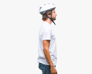 Handsome hispanic cyclist man wearing safety helmet over isolated background looking to side, relax profile pose with natural face with confident smile.