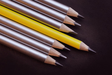 one lead pencil different from others on a black background