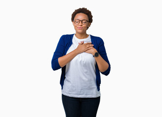 Young beautiful african american woman wearing glasses over isolated background smiling with hands on chest with closed eyes and grateful gesture on face. Health concept.