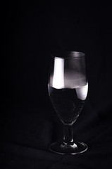  Silhouette wine glasses. A champagne glass filled with champagne on a black background and with beautiful voluminous highlights. A glass filled with smoke that comes out of it on a black background.