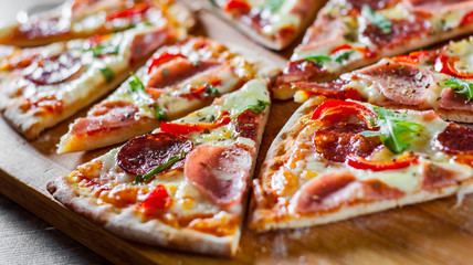 Pizza with Mozzarella cheese, ham, tomato sauce, salami, pepper, Spices and Fresh arugula. Italian pizza on wooden table background