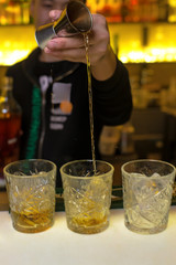 The bartender has prepared a cocktail and pours a cocktail into a glass