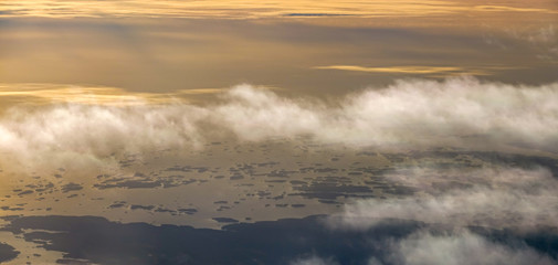The view from an airplane. Sunrise early morning. Clouds over archipelago landscape.