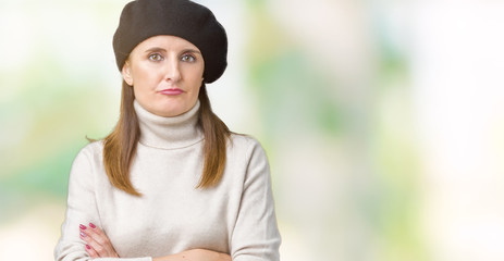 Middle age mature woman wearing winter sweater and beret over isolated background skeptic and nervous, disapproving expression on face with crossed arms. Negative person.