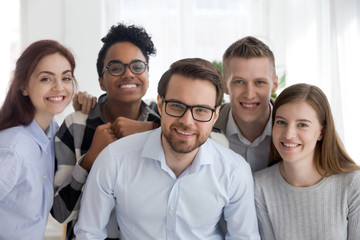 Portrait of smiling millennial multiracial office workers posing together, diverse young business...