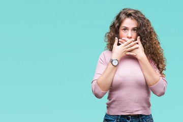 Beautiful brunette curly hair young girl wearing pink sweater over isolated background shocked covering mouth with hands for mistake. Secret concept.