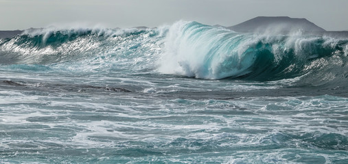 Fototapeta na wymiar Turquoise tunnel wave strike against shallow water. Atlantic ocean.