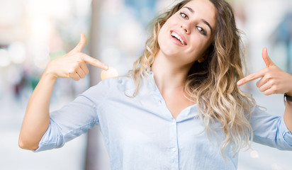 Beautiful young blonde business woman over isolated background looking confident with smile on face, pointing oneself with fingers proud and happy.