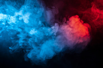 Clubs of isolated colored smoke: blue, red, orange, pink; scrolling on a black background in the dark close up.