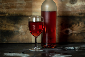 bottle and glass of red wine on rustic wooden background with spac for text or own brand