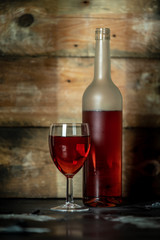 bottle and glass of red wine on rustic wooden background with space for text or own brand