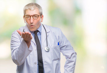 Handsome senior doctor man over isolated background looking at the camera blowing a kiss with hand on air being lovely and sexy. Love expression.