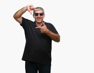 Fototapeta premium Handsome senior man wearing sunglasses over isolated background smiling making frame with hands and fingers with happy face. Creativity and photography concept.