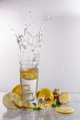 A glass of lemonade on a light background with splashing water