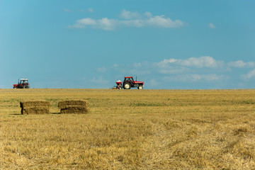 Two tractors driving across the stubble field