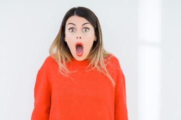 Young woman wearing casual red sweater over isolated background In shock face, looking skeptical and sarcastic, surprised with open mouth