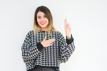Young woman wearing casual sweater over isolated background Swearing with hand on chest and...