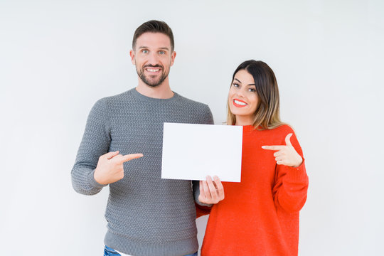 Young Couple Holding Blank Sheet Paper Over Isolated Background Very Happy Pointing With Hand And Finger